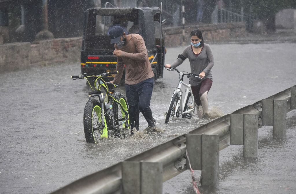 Las personas intentan caminar por las inundaciones en Gurgaon