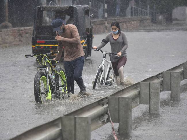 Las personas intentan caminar por las inundaciones en Gurgaon