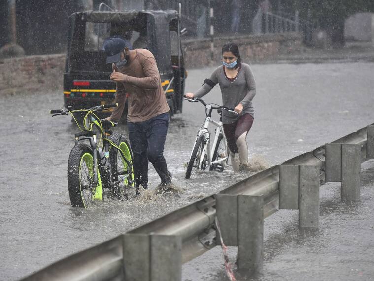 Las personas intentan caminar por las inundaciones en Gurgaon