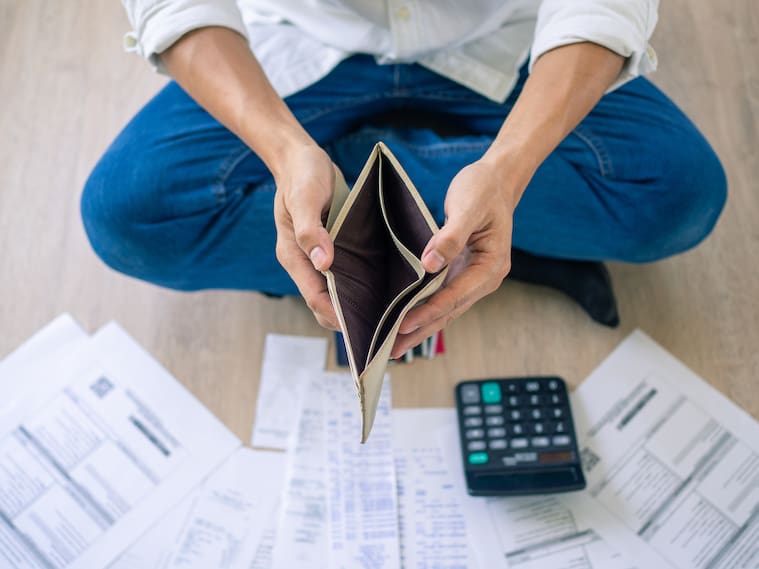 A businessman who is sitting on the floor of the house opening the wallet but have to pay debt Calculation of large amounts of expenses. Debt concepts