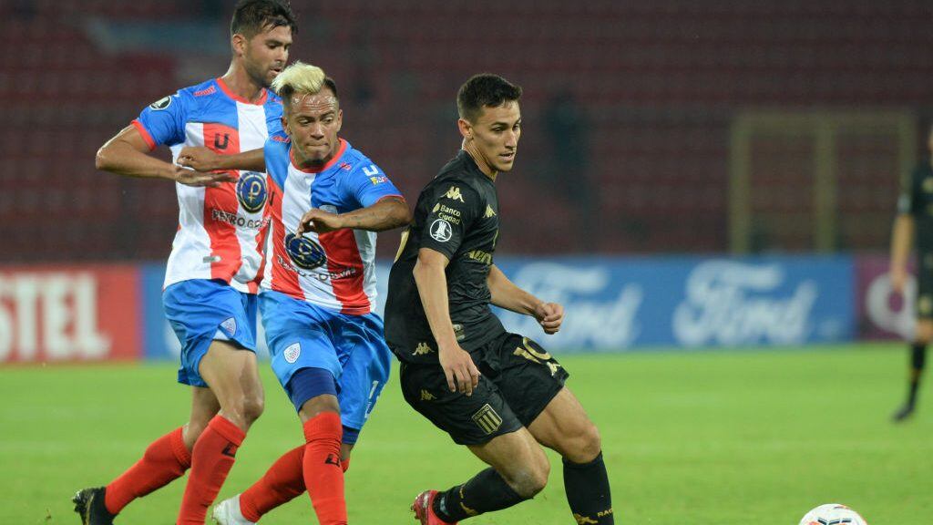 Argentina's Racing Club midfielder Matias Rojas and Venezuela's Estudiantes de Merida midfielder Christian Flores (C) vie for the ball during their Copa Libertadores football match, at the Metropolitano stadium in Merida on March 5, 2020. (Photo by CARLOS EDUARDO RAMIREZ / AFP) (Photo by CARLOS EDUARDO RAMIREZ/AFP via Getty Images)