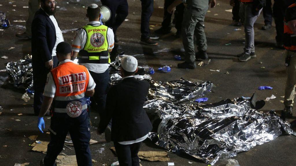 Paramedics and ultra-Orthodox Jewish men stand next to covered bodies after dozens of people were killed and others injured after a grandstand collapsed in Meron, Israel, where tens of thousands of people were gathered to celebrate the festival of Lag Ba'omer at the site in northern Israel early on April 30, 2021. - Dozens of people were killed in a stampede at a Jewish pilgrimage site in the north of Israel on early on April 30, rescue services said. Tens of thousands of Jews were participating in the annual pilgrimage on Thursday, for the feast of Lag BaOmer. But after midnight, a grandstand collapsed, triggering scenes of panic. - Israel OUT (Photo by David COHEN / JINI PIX / AFP) / Israel OUT (Photo by DAVID COHEN/JINI PIX/AFP via Getty Images)