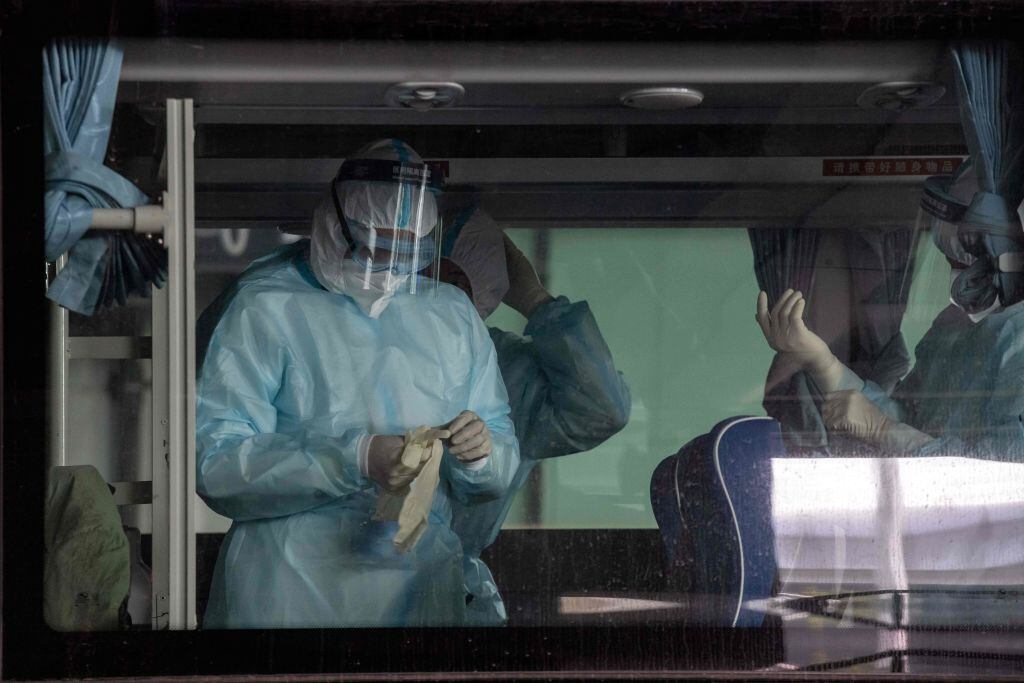 Trabajadores desinfectan el bus que trasladará a los expertos de la OMS en China