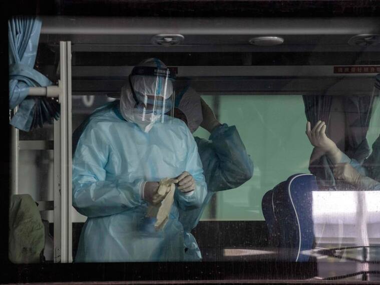 Trabajadores desinfectan el bus que trasladará a los expertos de la OMS en China