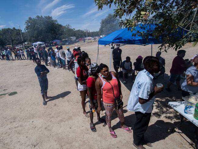 Migrantes esperan en una fila para recibir comida en Ciudad Acuña