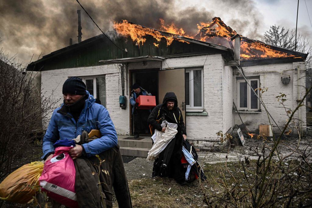 Familia saca pertenencias en medio de un incendio en Irpín cerca de Kiev