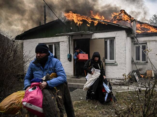 Familia saca pertenencias en medio de un incendio en Irpín cerca de Kiev