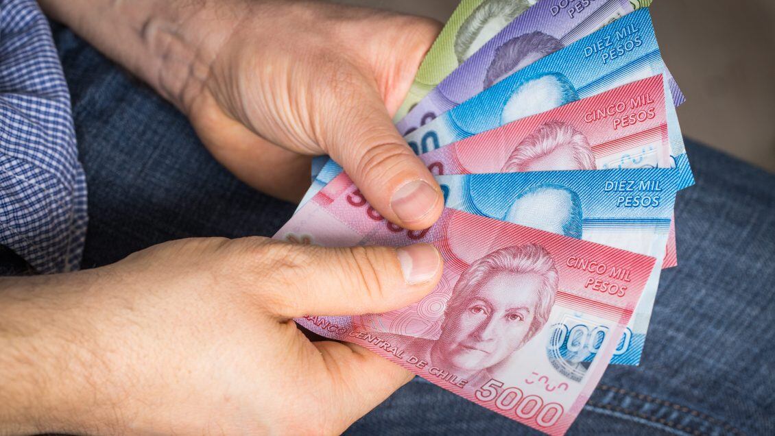 a man holding Chilean money in his hand, Pesos of various values
