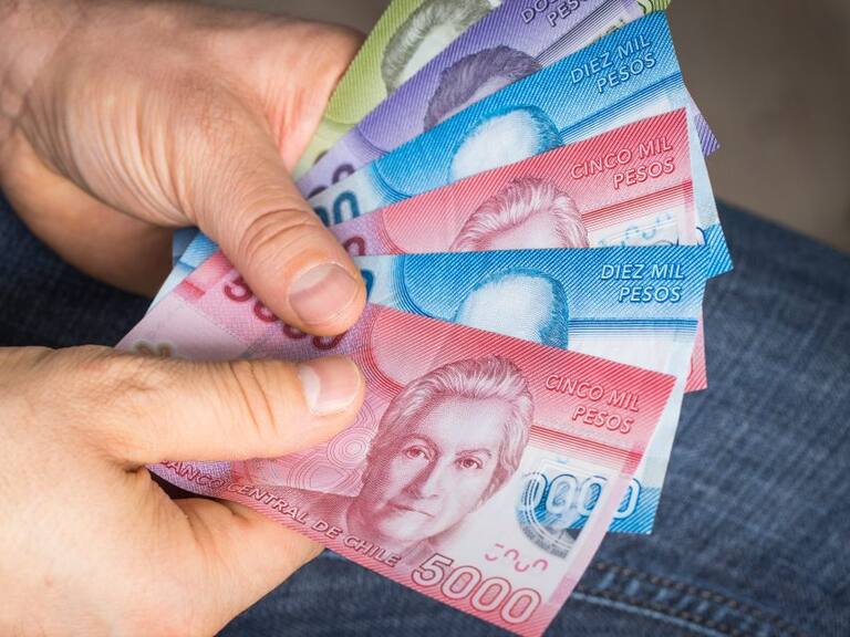 a man holding Chilean money in his hand, Pesos of various values