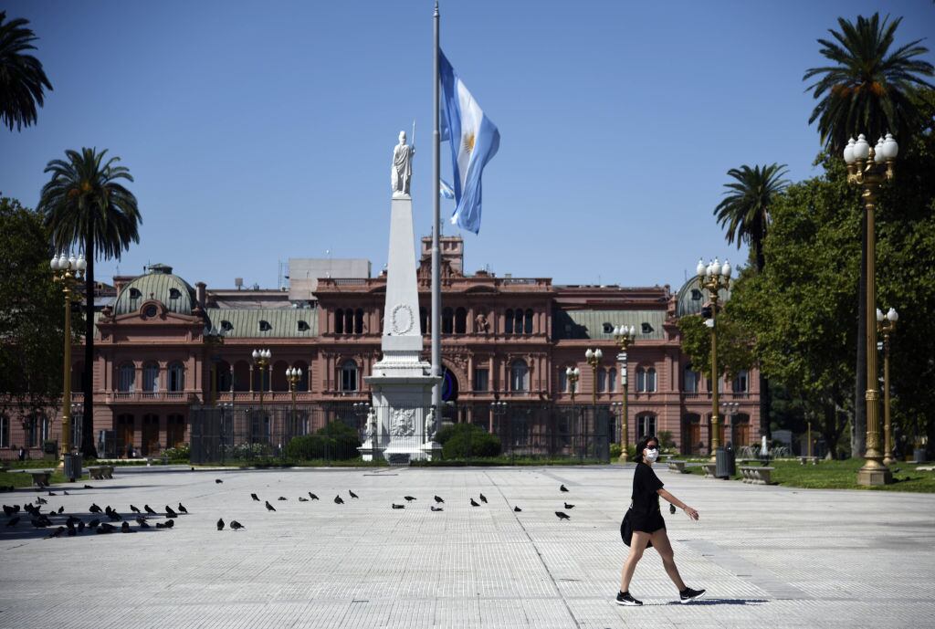 Una mujer camina frente al Palacio de la Casa Rosada en una vacía ciudad de Buenos Aires