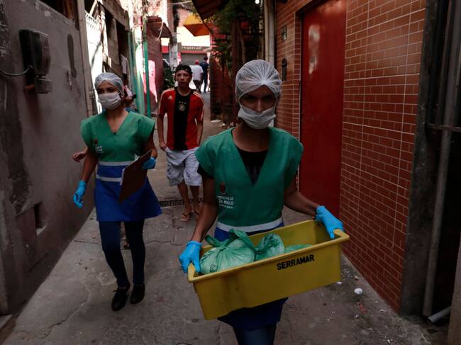Unos voluntarios entregan alimentos a los habitantes de la favela Paraisopolis en Sao Paulo