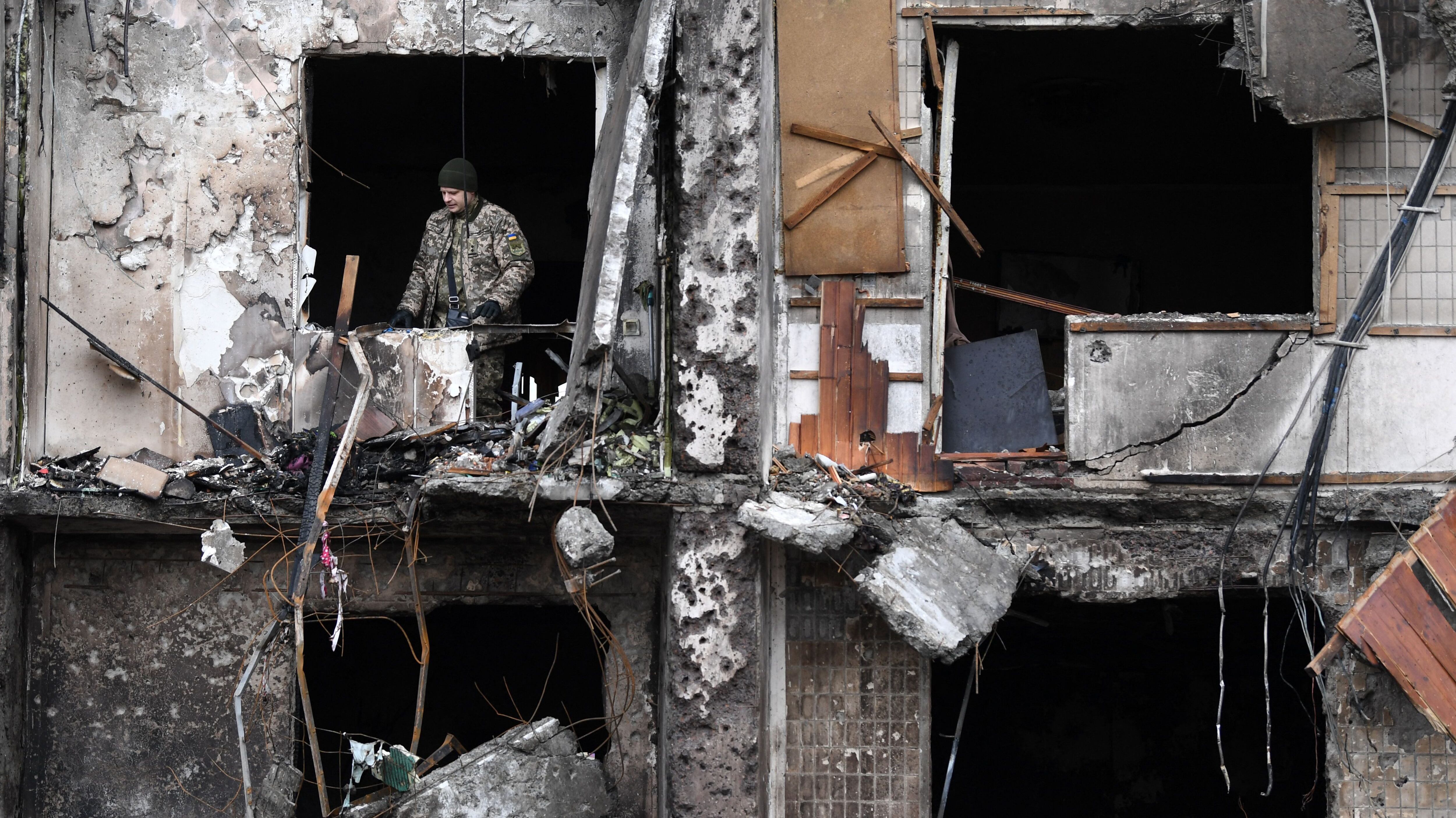 A Ukrainian serviceman is seen in the window of a damaged residential building at Koshytsa Street, a suburb of the Ukrainian capital Kyiv, where a military shell allegedly hit, on February 25, 2022. - Russian forces reached the outskirts of Kyiv on Friday as Ukrainian President Volodymyr Zelensky said the invading troops were targeting civilians and explosions could be heard in the besieged capital. Pre-dawn blasts in Kyiv set off a second day of violence after Russian President Vladimir Putin defied Western warnings to unleash a full-scale ground invasion and air assault on Thursday that quickly claimed dozens of lives and displaced at least 100,000 people. (Photo by Daniel LEAL / AFP) (Photo by DANIEL LEAL/AFP via Getty Images)