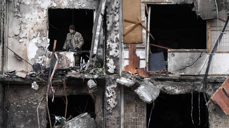 A Ukrainian serviceman is seen in the window of a damaged residential building at Koshytsa Street, a suburb of the Ukrainian capital Kyiv, where a military shell allegedly hit, on February 25, 2022. - Russian forces reached the outskirts of Kyiv on Friday as Ukrainian President Volodymyr Zelensky said the invading troops were targeting civilians and explosions could be heard in the besieged capital. Pre-dawn blasts in Kyiv set off a second day of violence after Russian President Vladimir Putin defied Western warnings to unleash a full-scale ground invasion and air assault on Thursday that quickly claimed dozens of lives and displaced at least 100,000 people. (Photo by Daniel LEAL / AFP) (Photo by DANIEL LEAL/AFP via Getty Images)