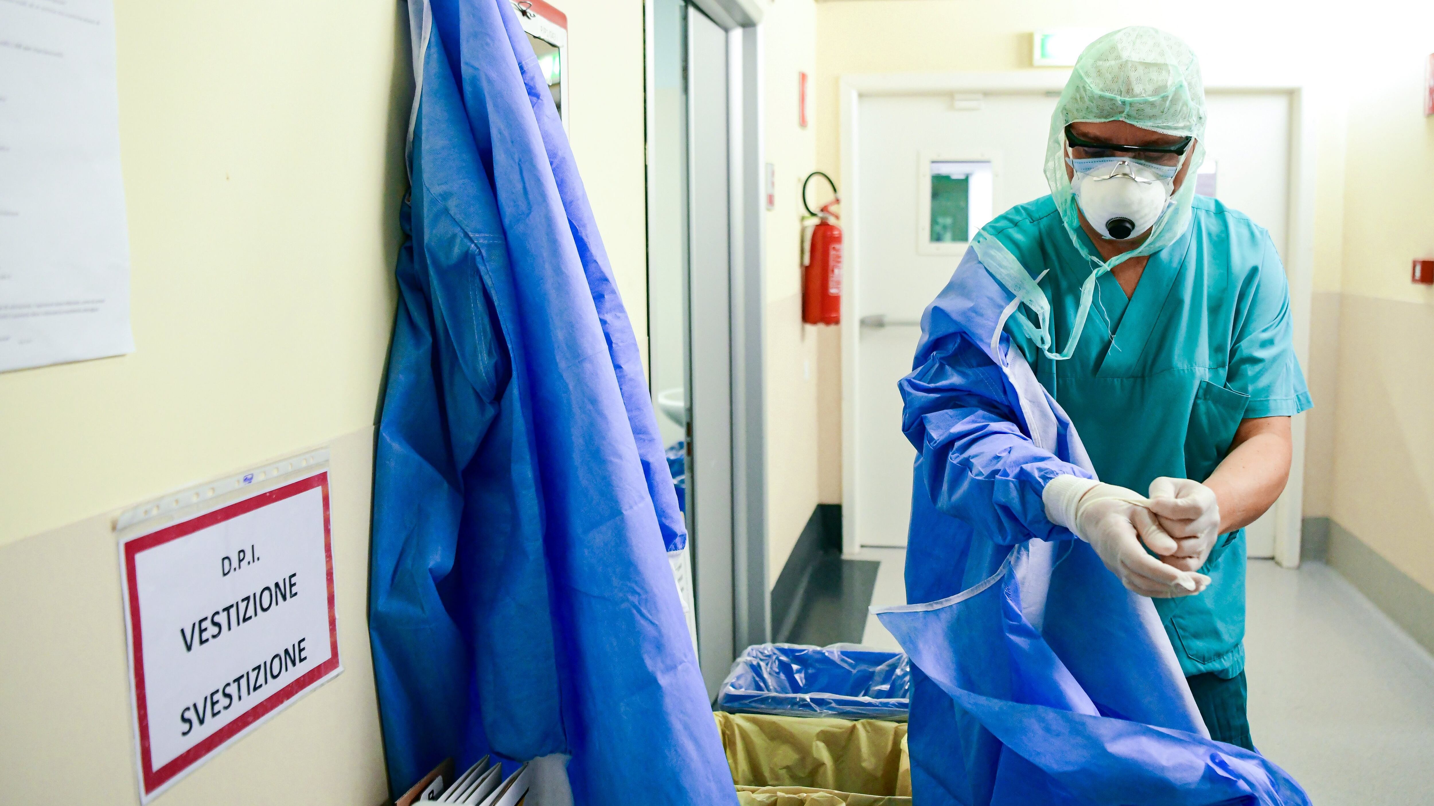 A member of the medical staff takes of his Personal Protective Equipment (PPE) after working at the COVID-19 division at the ASST Papa Giovanni XXIII hospital in Bergamo, on April 3, 2020. - Italy's three-week lockdown to stop the spread of COVID-19 has been extended through at least mid-April and its economy is expected to suffer its biggest peacetime shock since World War II. (Photo by Piero CRUCIATTI / AFP) (Photo by PIERO CRUCIATTI/AFP via Getty Images)