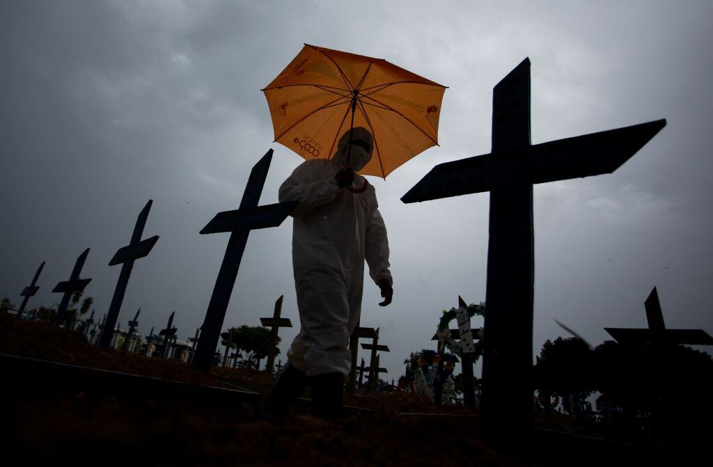 Trabajador camina ante víctimas del Covid-19 en cementerio de Brasil