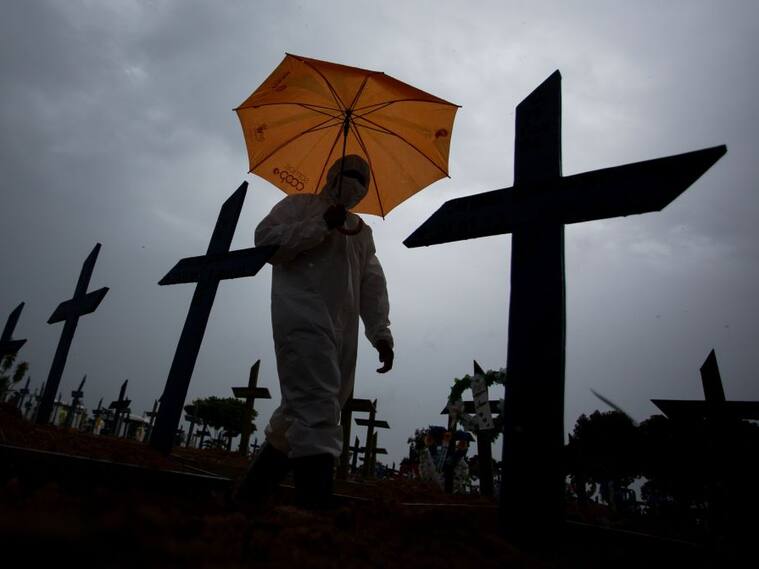 Trabajador camina ante víctimas del Covid-19 en cementerio de Brasil