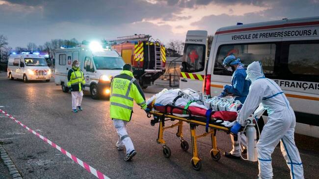 TOPSHOT - Emergency medical personnel carries a patient affected with coronavirus (Covid-19) from a military hospital to an ambulance before being transported aboard a medicalised TGV (high-speed train) to be evacuated towards hospitals of other French regions on March 29, 2020 in Mulhouse, eastern France, amid the spread of the COVID-19 (new coronavirus) pandemic. - (Photo by SEBASTIEN BOZON / AFP) (Photo by SEBASTIEN BOZON/AFP via Getty Images)