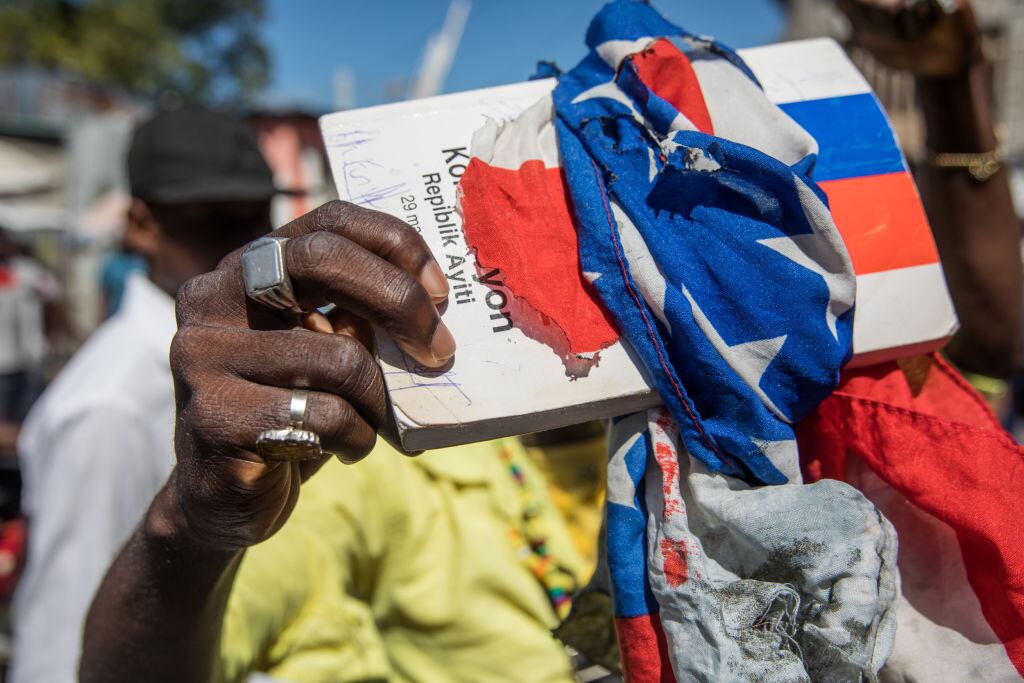 Un manifestante envuelve la constitución con la bandera haitiana en una marcha contra Moise
