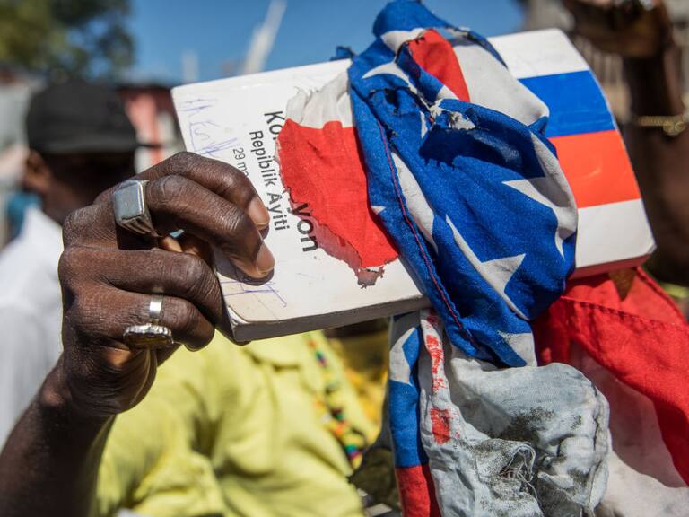 Un manifestante envuelve la constitución con la bandera haitiana en una marcha contra Moise