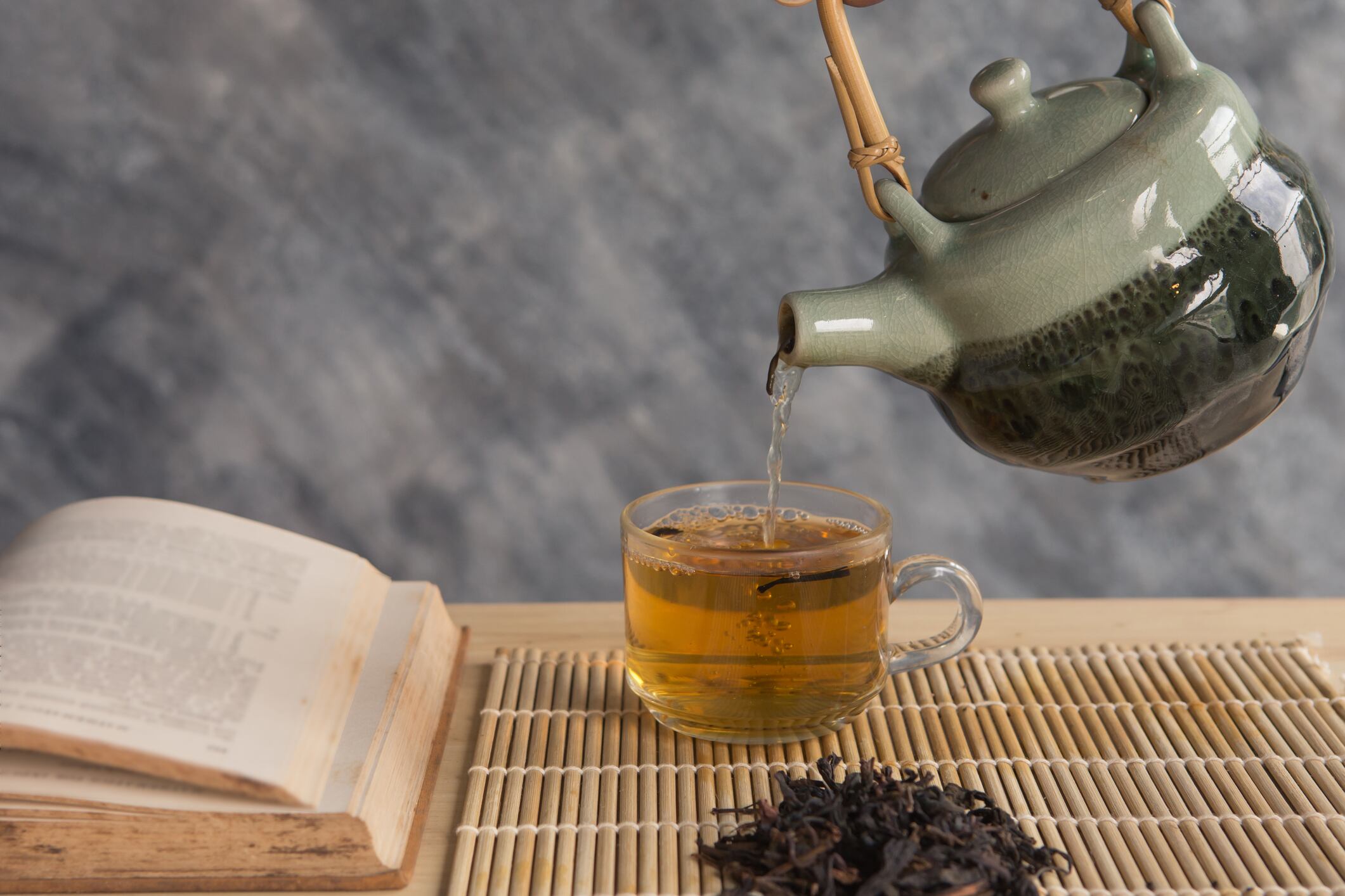 Teapot pouring tea into the cup with reading book
