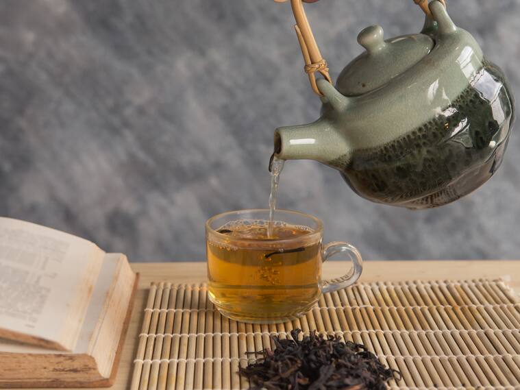 Teapot pouring tea into the cup with reading book