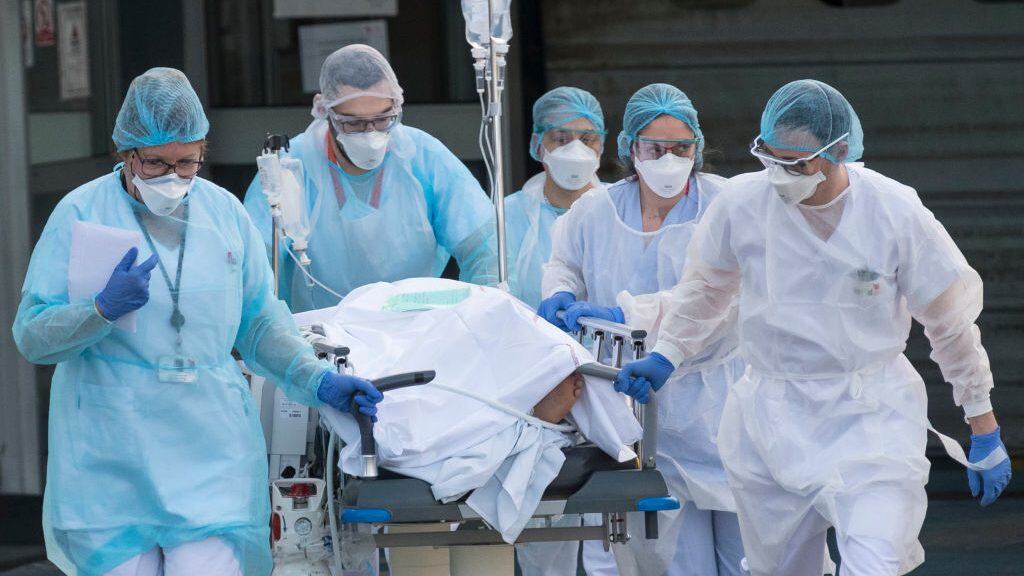 TOPSHOT - Medical staff push a patient on a gurney to a waiting medical helicopter at the Emile Muller hospital in Mulhouse, eastern France, to be evacuated on another hospital on March 17, 2020, amid the outbreak of the new Coronavirus, COVID-19. - A strict lock down requiring most people in France to remain at home came into effect at midday on March 17, 2020, prohibiting all but essential outings in a bid to curb the coronavirus spread. The country has reported 148 deaths from the virus, a number that health experts warn could soar in the coming days, seriously straining the hospital system. (Photo by SEBASTIEN BOZON / AFP) (Photo by SEBASTIEN BOZON/AFP via Getty Images)