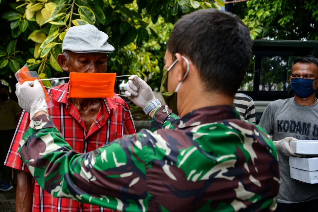 Un soldado enseña a una persona a colocarse una mascarilla en Indonesia