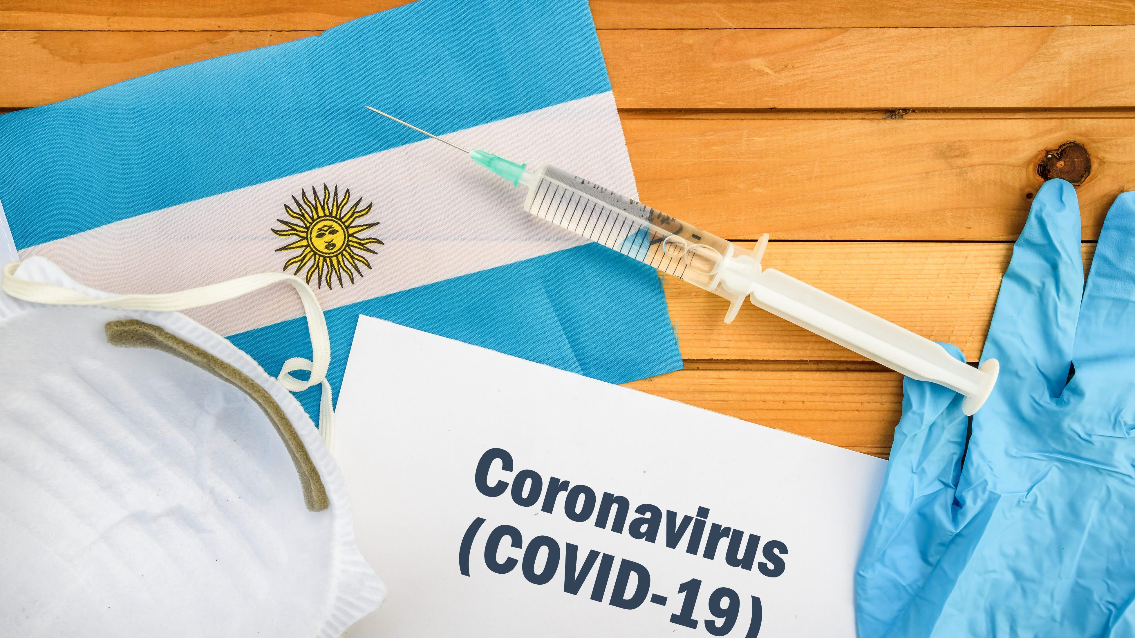 Flag of Argentina , vaccine, face mask for virus, glove and paper sheet with words Coronavirus COVID-19