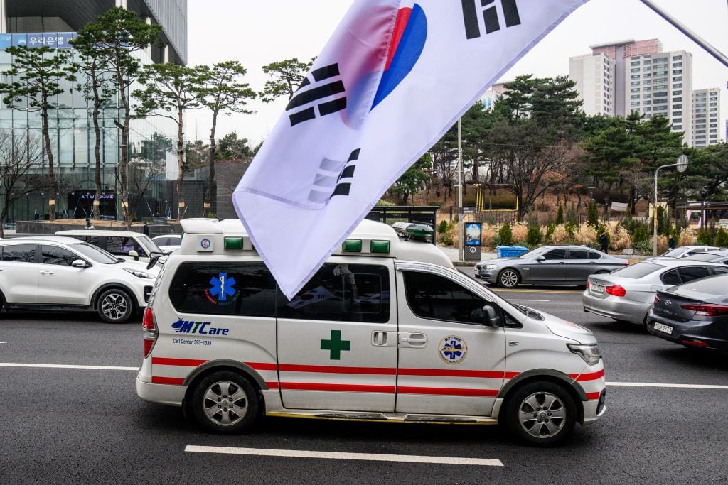 Una ambulancia pasa ante una bandera de Corea del Sur, en medio de una huelga general de los médicos en ese país asiático.