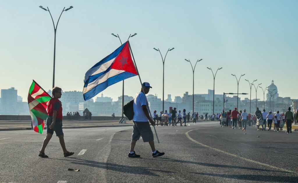 Personas caminan con la bandera de Cuba y del País Vasco tras participar de una manifestación en la ciudad de La Habana