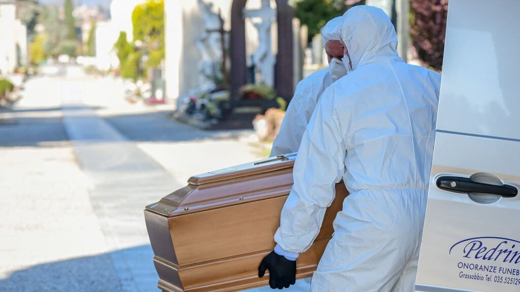 Undertakers wearing a face mask and overalls unload a coffin out of a hearse on March 16, 2020 at the Monumental cemetery of Bergamo, Lombardy, as burials of people who died of the new coronavirus are being conducted at the rythm of one every half hour. (Photo by Piero Cruciatti / AFP) (Photo by PIERO CRUCIATTI/AFP via Getty Images)