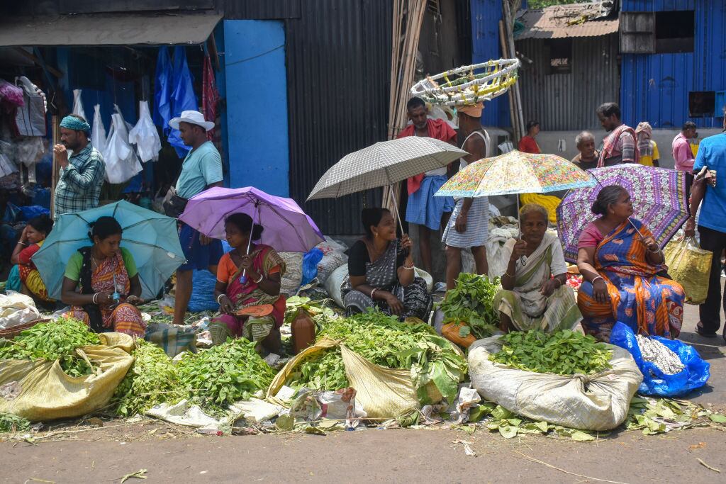 Un grupo de mujeres se resguardan con paraguas y sombrillas de las altas temperaturas en la ciudad de Calcuta en India.