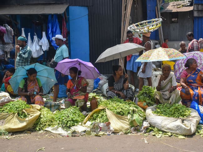 Un grupo de mujeres se resguardan con paraguas y sombrillas de las altas temperaturas en la ciudad de Calcuta en India.