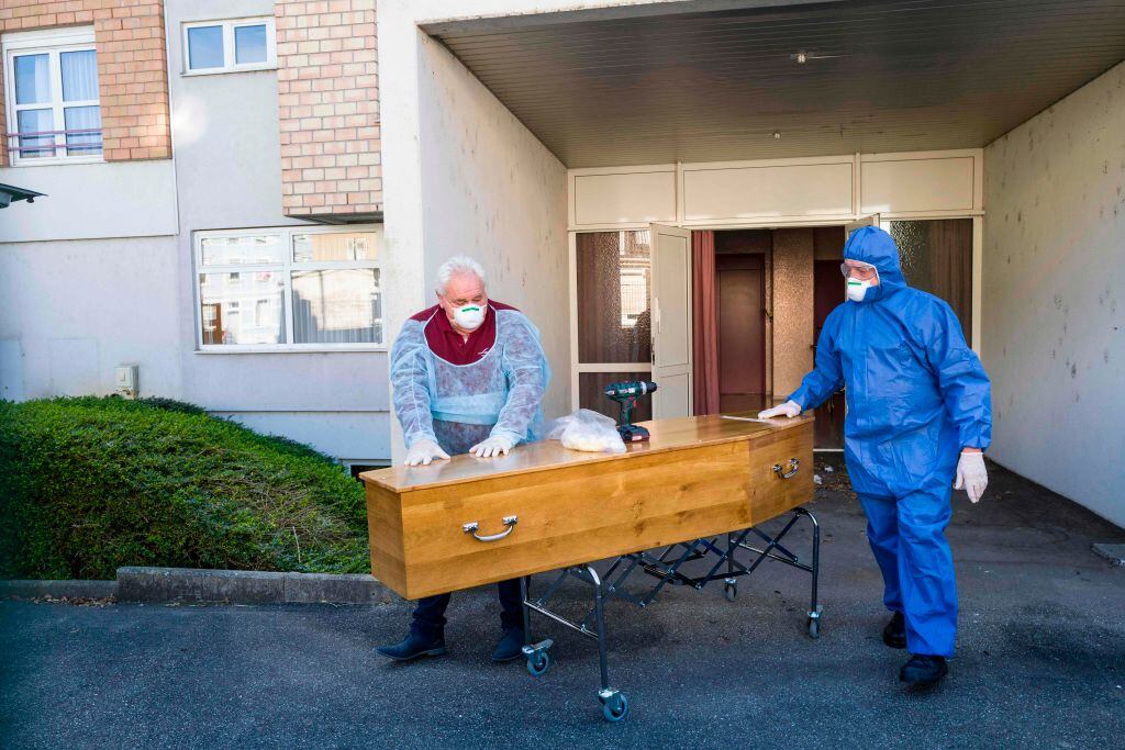 Trabajadores de una funeraria transportan el féretro de una víctima del Covid-19 en Francia