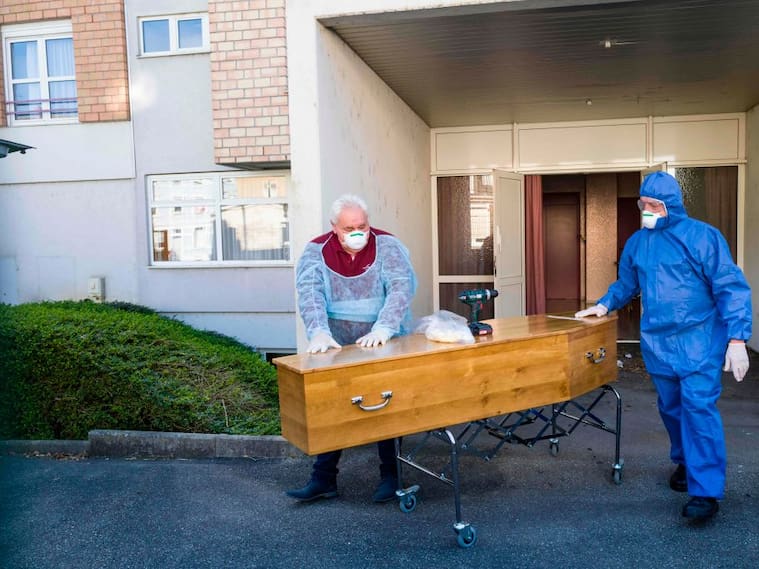 Trabajadores de una funeraria transportan el féretro de una víctima del Covid-19 en Francia