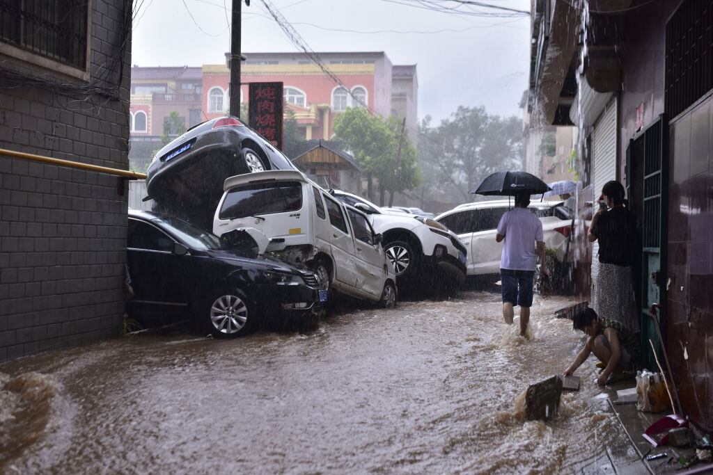 Vehículos acumulados por el agua y las personas que observan la inundación en China