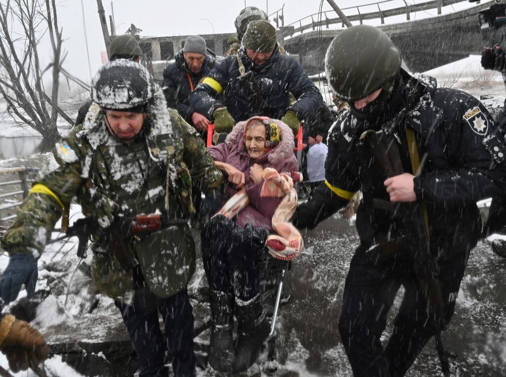 Ukrainian soldiers help an elderly woman to cross a destroyed bridge as she evacuates the city of Irpin, northwest of Kyiv, on March 8, 2022. - More than two million people have fled Ukraine since Russia launched its full-scale invasion less than two weeks ago, the United Nations said on March 8, 2022. (Photo by Sergei SUPINSKY / AFP) (Photo by SERGEI SUPINSKY/AFP via Getty Images)