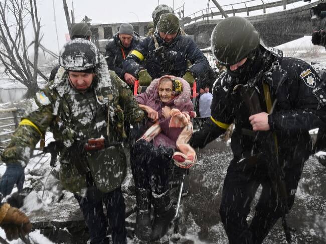 Ukrainian soldiers help an elderly woman to cross a destroyed bridge as she evacuates the city of Irpin, northwest of Kyiv, on March 8, 2022. - More than two million people have fled Ukraine since Russia launched its full-scale invasion less than two weeks ago, the United Nations said on March 8, 2022. (Photo by Sergei SUPINSKY / AFP) (Photo by SERGEI SUPINSKY/AFP via Getty Images)