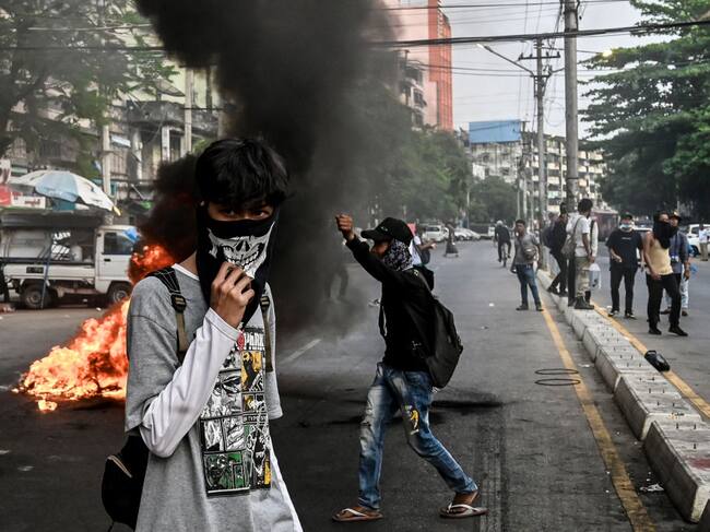 Manifestantes incendian una barricada para impedir el paso de agentes de la dictadura en Rangún