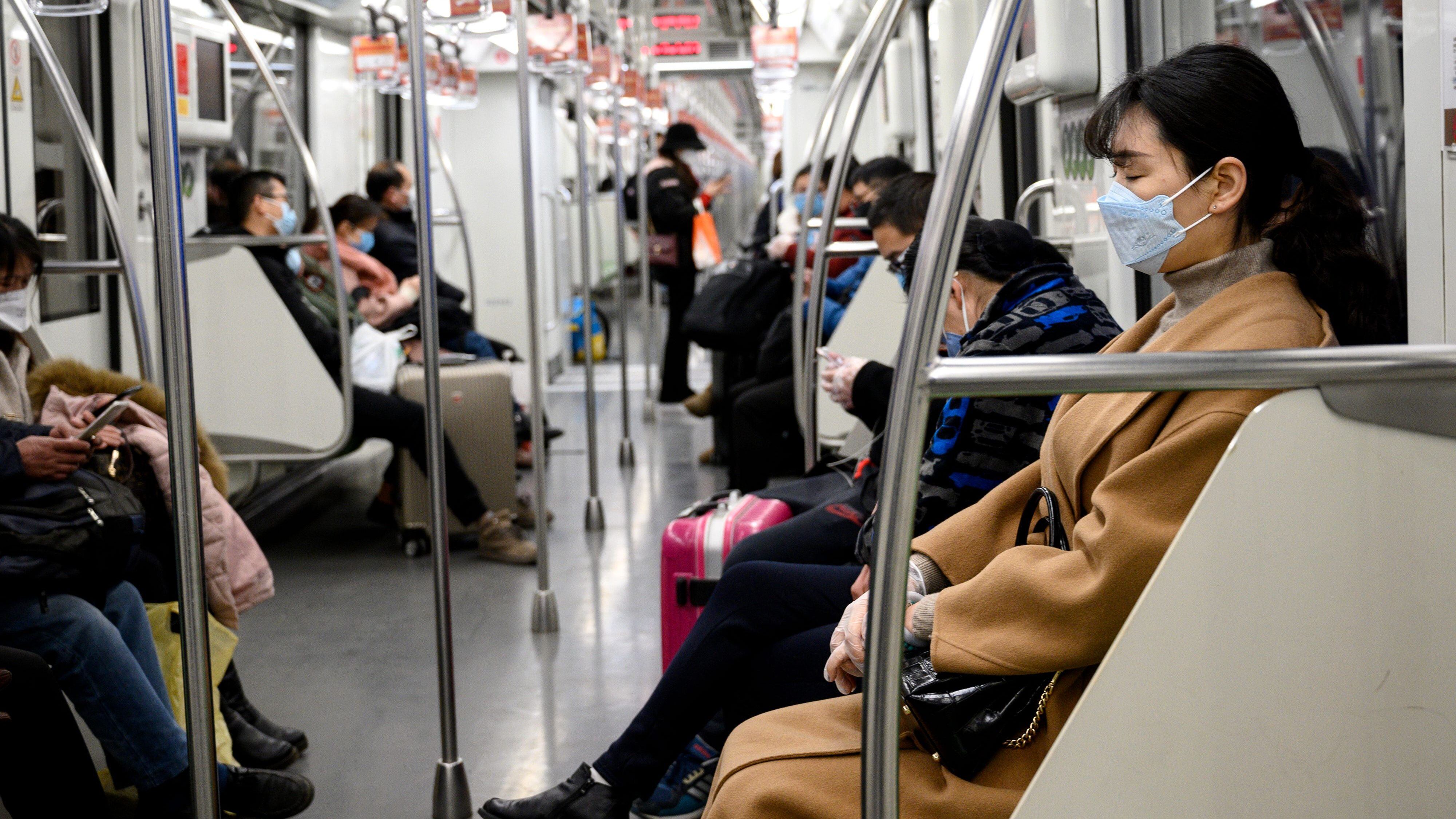 People wearing protective face masks commute on a train in Shanghai on February 10, 2020. - The death toll from the novel coronavirus surged past 900 in mainland China on February 10, overtaking global fatalities in the 2002-03 SARS epidemic, even as the World Health Organization said the outbreak appeared to be stabilising. (Photo by NOEL CELIS / AFP) (Photo by NOEL CELIS/AFP via Getty Images)