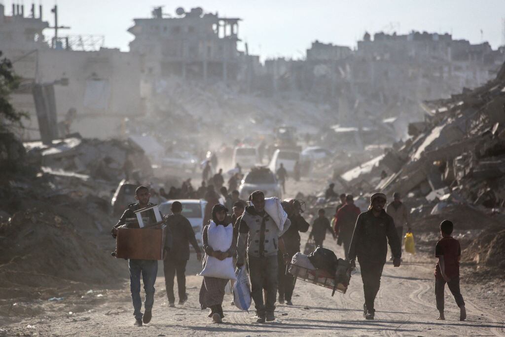 Palestinos desplazados caminan en medio de las ruinas que dejan los ataques militares de Israel sobre la Franja de Gaza en Palestina