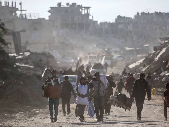 Palestinos desplazados caminan en medio de las ruinas que dejan los ataques militares de Israel sobre la Franja de Gaza en Palestina