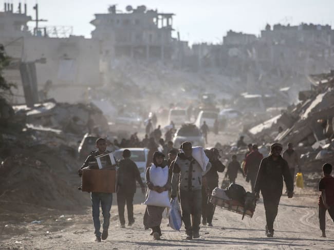 Palestinos desplazados caminan en medio de las ruinas que dejan los ataques militares de Israel sobre la Franja de Gaza en Palestina
