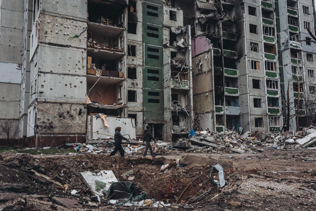 Una pareja pasa ante un edificio destruido en la ciudad de Chernihiv