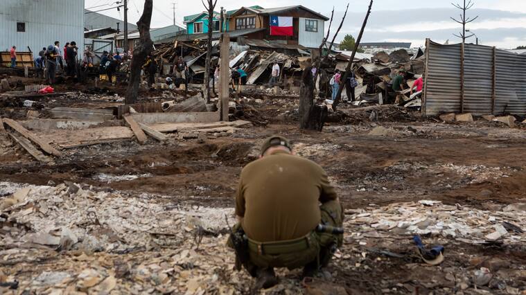 10 DE DICIEMBRE 2021 / CASTROUn carabinero agachado revisa los escombros tras incendio forestal que destruyo más de 140 casas en la población Camilo Henrriquez y Villa los Presidentes, durante mega incendio en la ciudad de Castro, Chiloé.
FOTO: FELIPE CONSTANZO / AGENCIAUNO