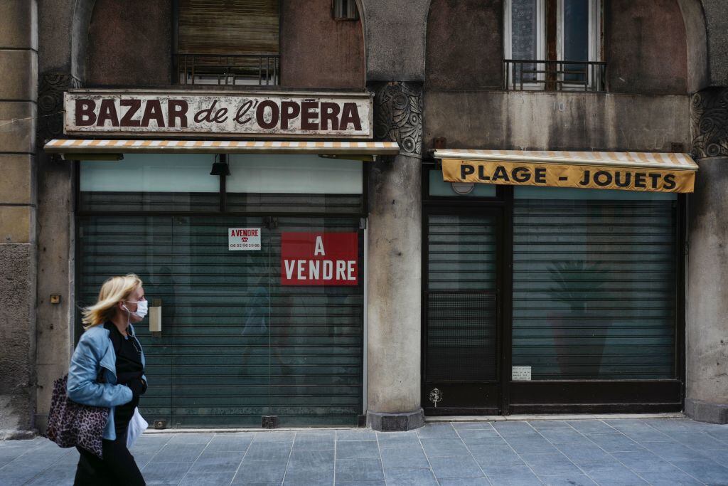 Una mujer camina delante de tiendas cerradas y en venta en Niza