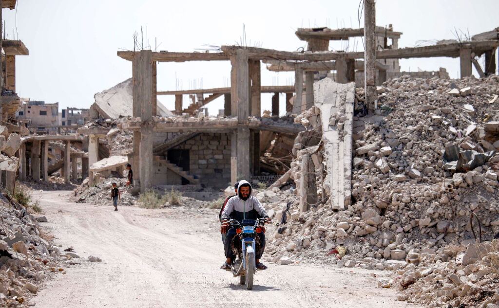 Personas avanzan entre las ruinas que deja la guerra en Siria