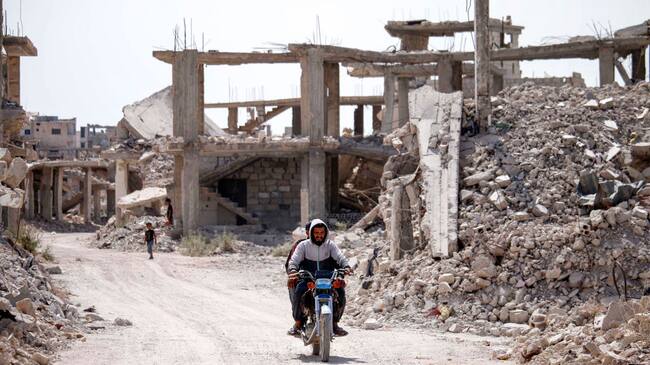 Personas avanzan entre las ruinas que deja la guerra en Siria
