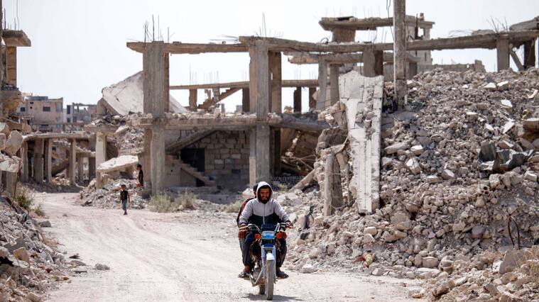 Personas avanzan entre las ruinas que deja la guerra en Siria