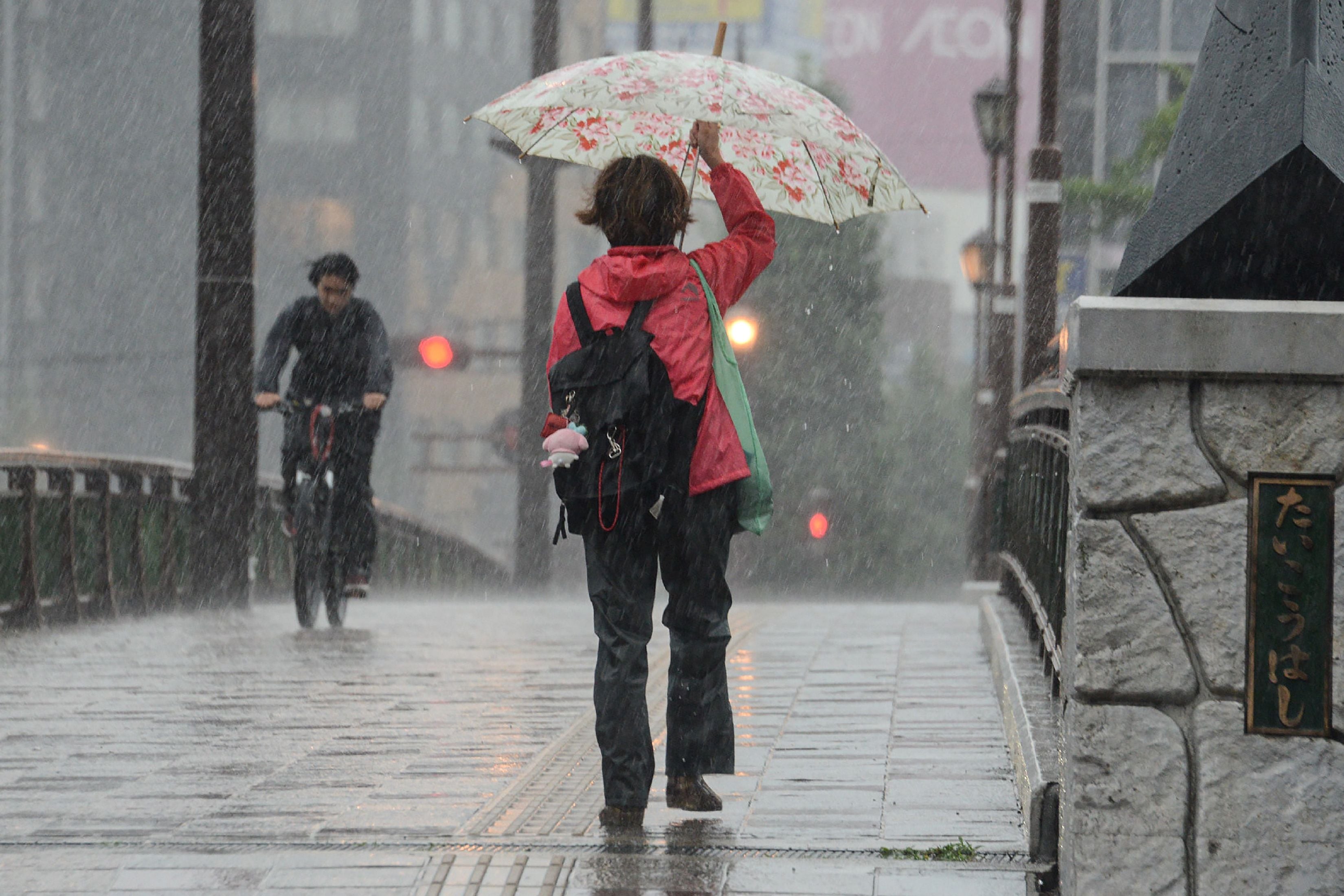 Mujer se cubre de las fuertes lluvias en la isla de Kyushu en Japón